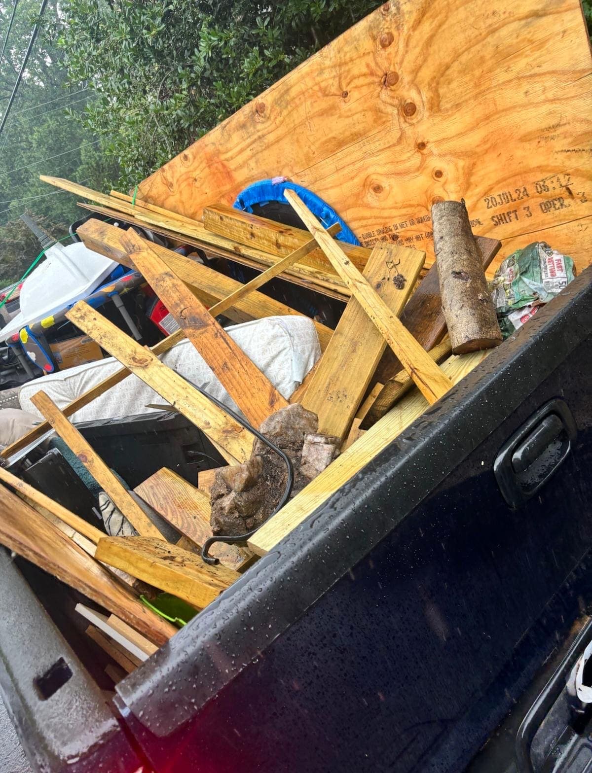 Close view of lumber, plywood, and a log stacked in a pickup bed.